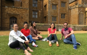 Students sit and smile in front of the Wroxton Abbey