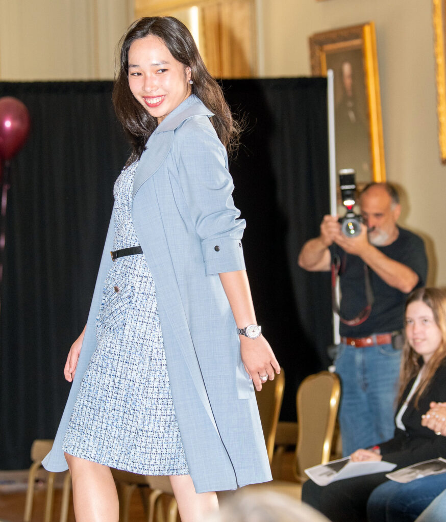 A female model walks down the runway to model women's businesswear. 