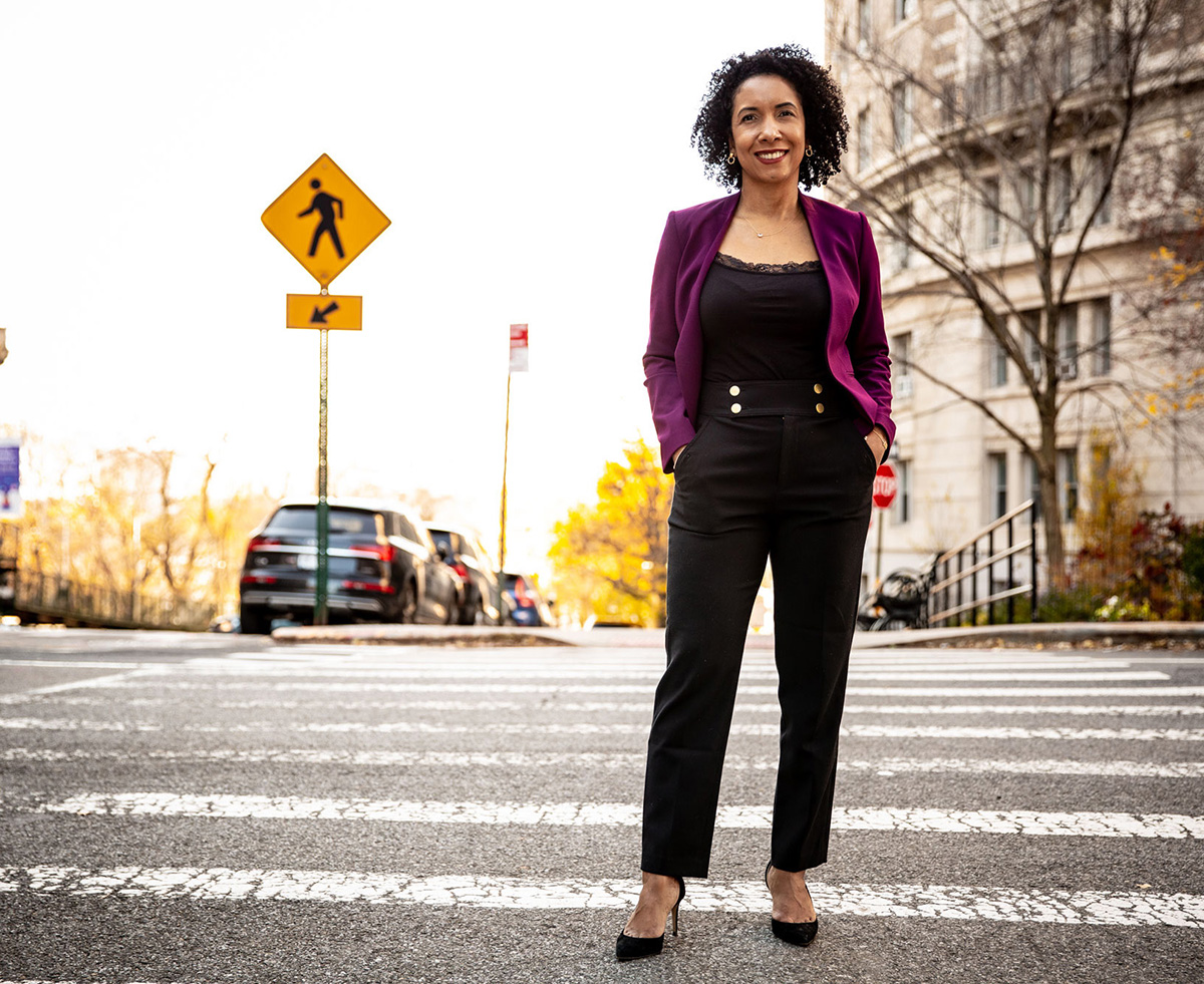 A woman poses for a photo in the crosswalk on a street in New York City.