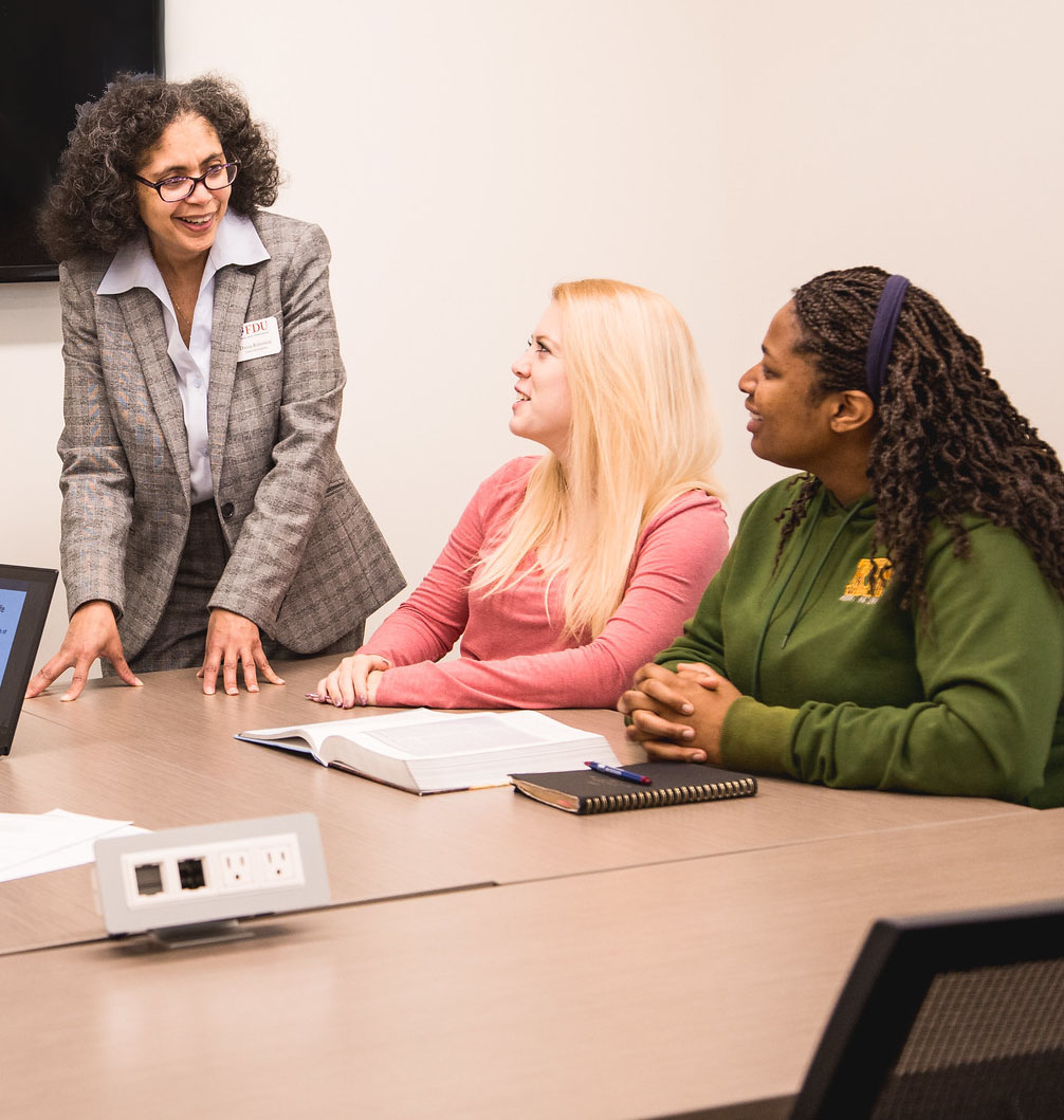 A female instructor speaks with two students.