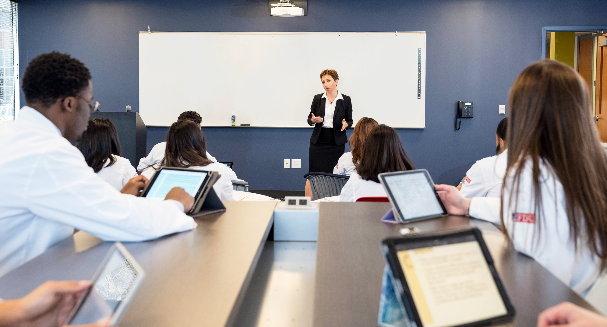 A female pharmacy professor delivers a lecture to her students.