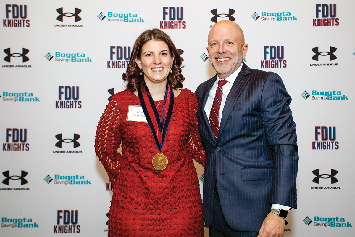 A man and woman pose together in front of a Knights backdrop.