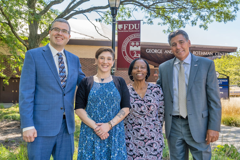 Two faculty members and two staff members stand in a line, posing for a photo.