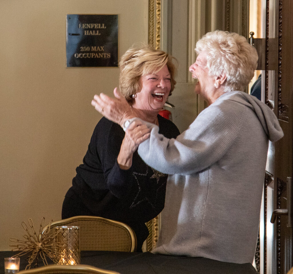 Two women chat and share an embrace.