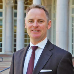 Portrait of a man wearing a suit and standing outside.