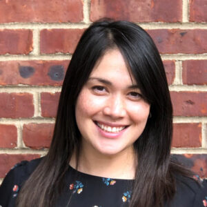 Portrait of a woman standing in front of a brick wall.