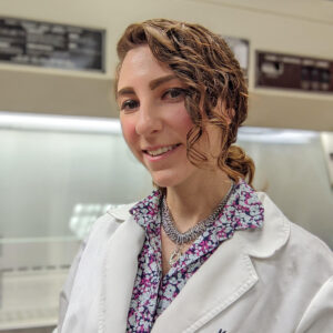 Portrait of a woman in a lab, wearing a white lab coat.