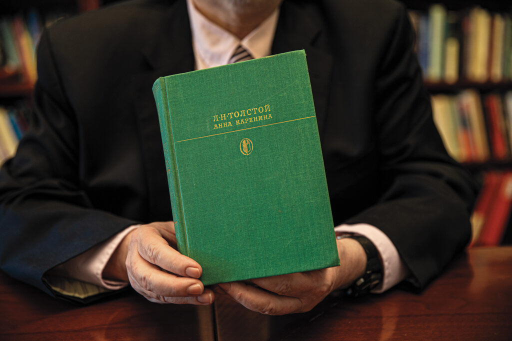 A man's hands hold up a book with a green cover.