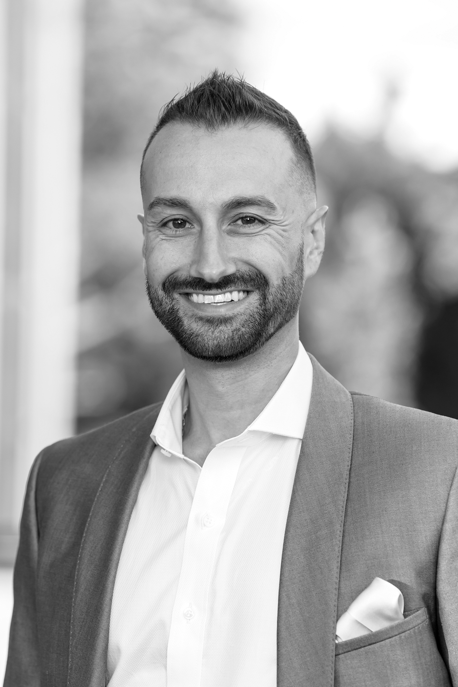 A portrait headshot of a man. The photo is in black and white.