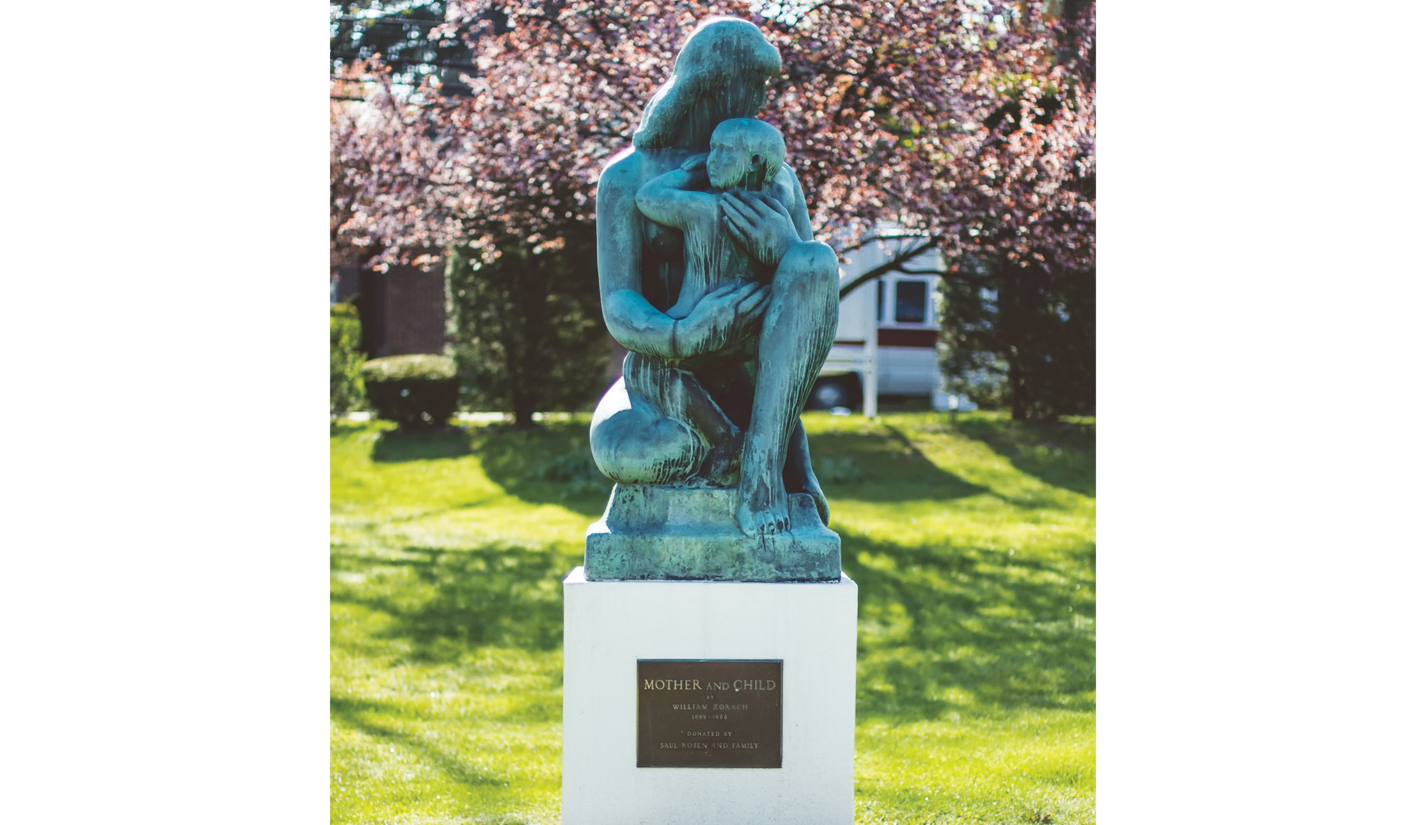Mother and Child sculpture in spring, with trees blooming behind the statue.