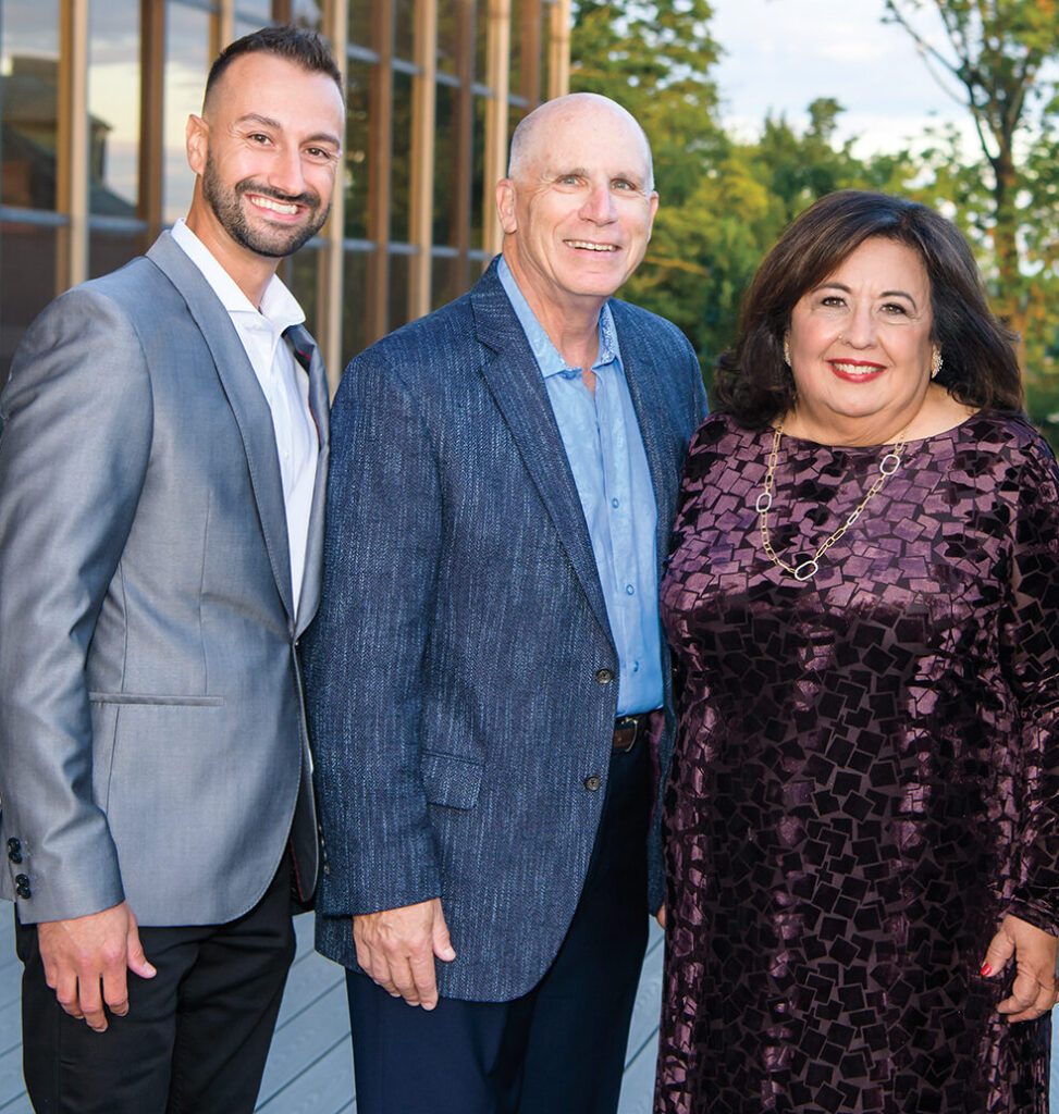 Three men and a woman pose together. 