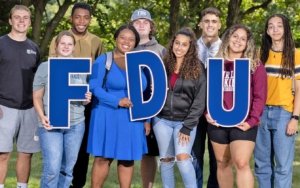 Smiling students hold up letters spelling F-D-U.