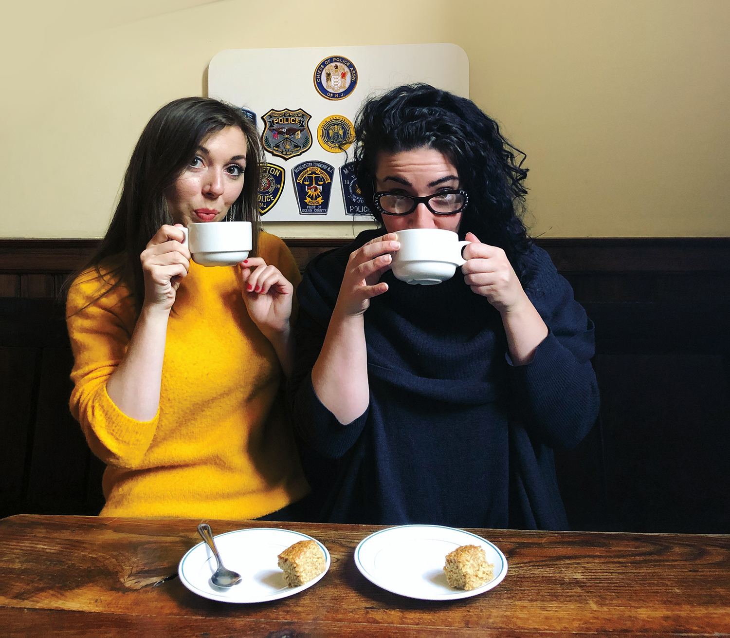 Two young women sip tea.