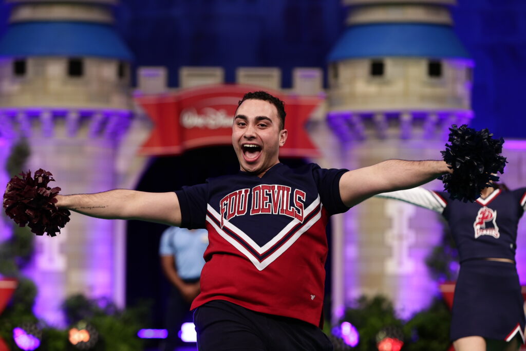 A male cheerleader smiles as he performs. 