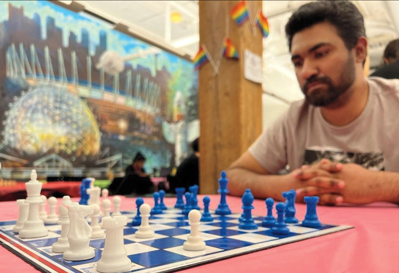 A man sits at a chess board, contemplating his next move.