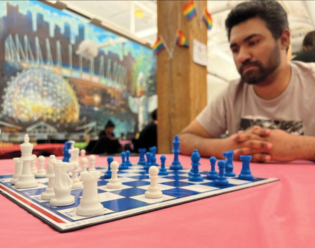A man sits at a chess board, contemplating his next move.
