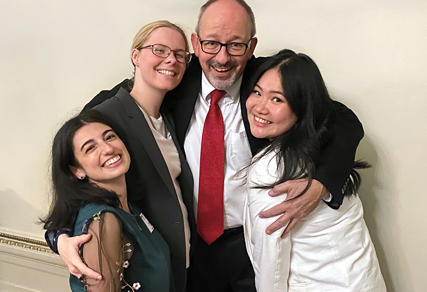 Three young women squeeze together for a photo with a man.