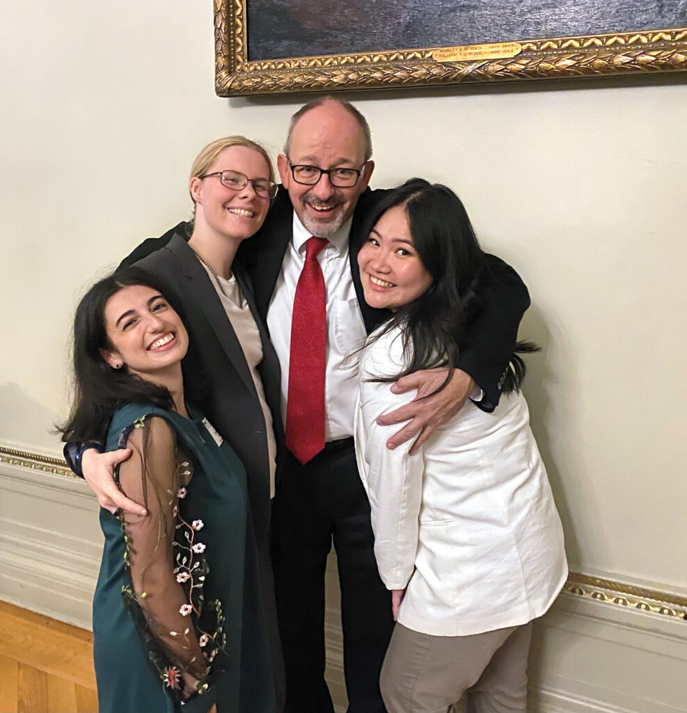 Three females smile and pose with a man. 