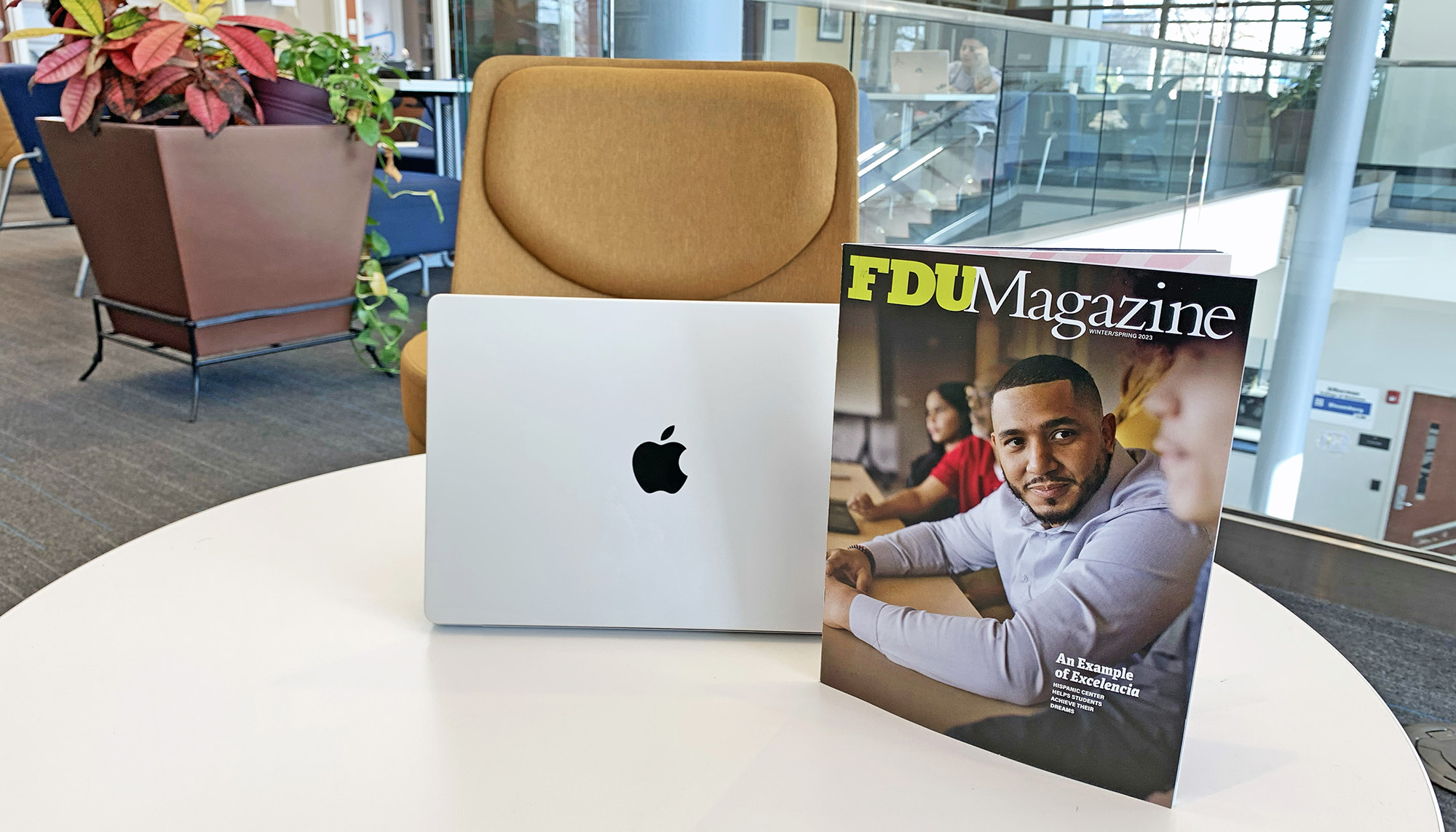 A Macbook and a copy of FDU Magazine sit on a table in the library.