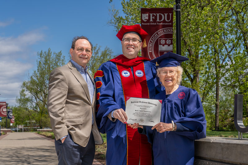 A professor, a college president and a 90-year-old graduate student smile for a photo.
