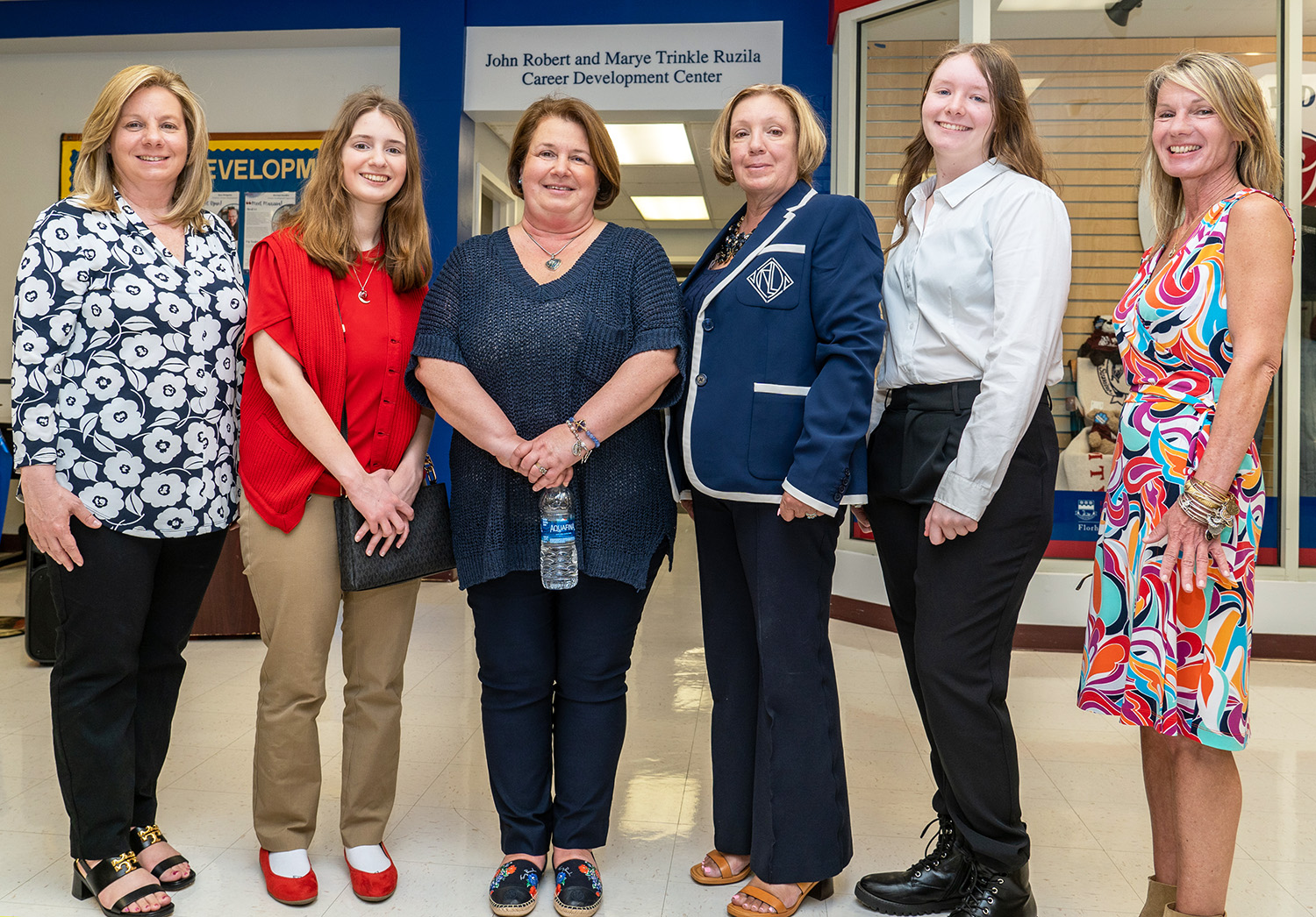 Six women of various ages and generations pose for a photo.