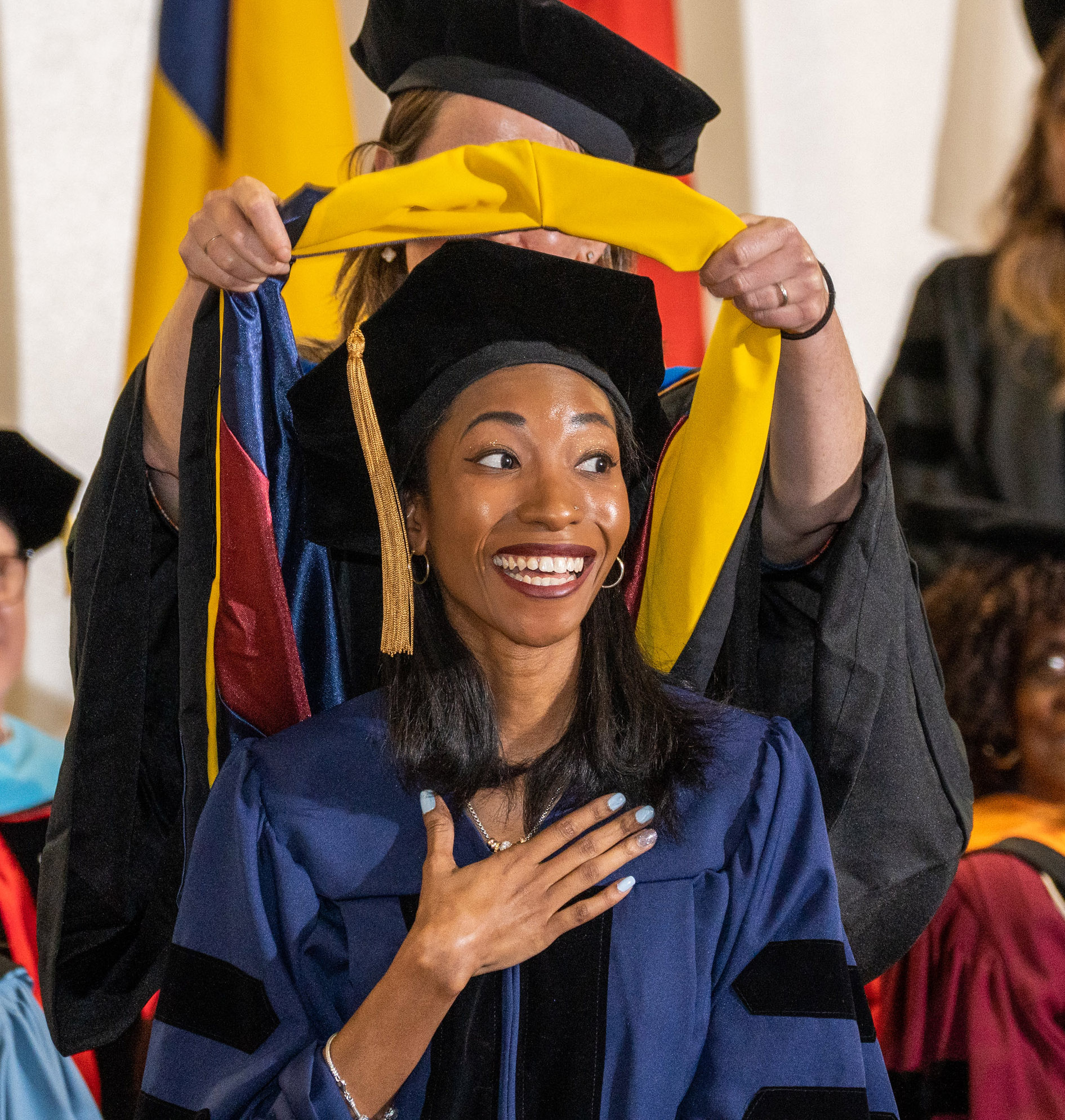 A young woman receives her doctoral hood.