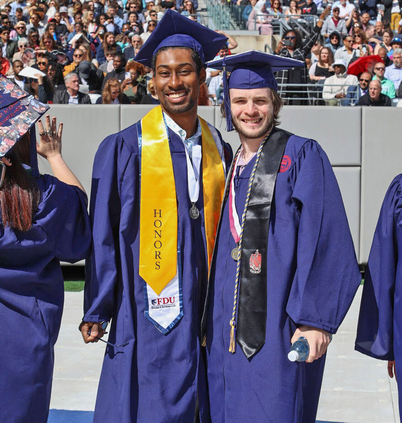 Two graduates in regalia pose for a photo.