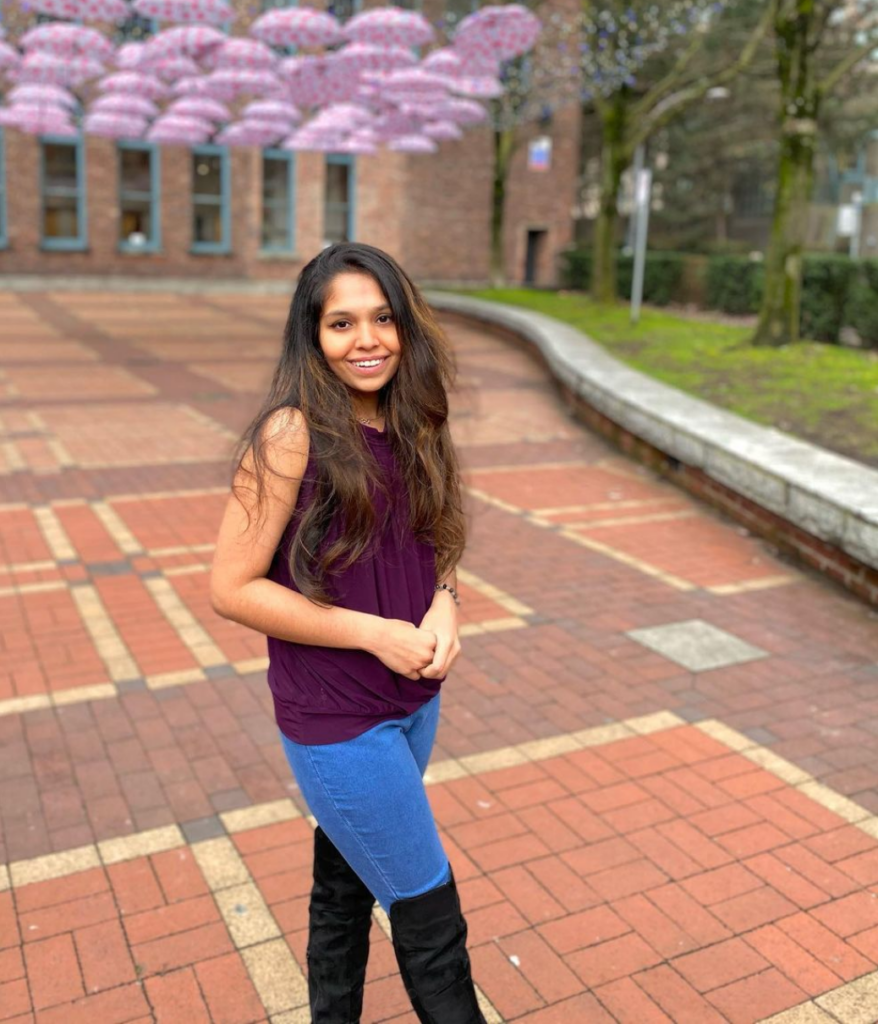 A young woman poses for a photo in a brick plaza.