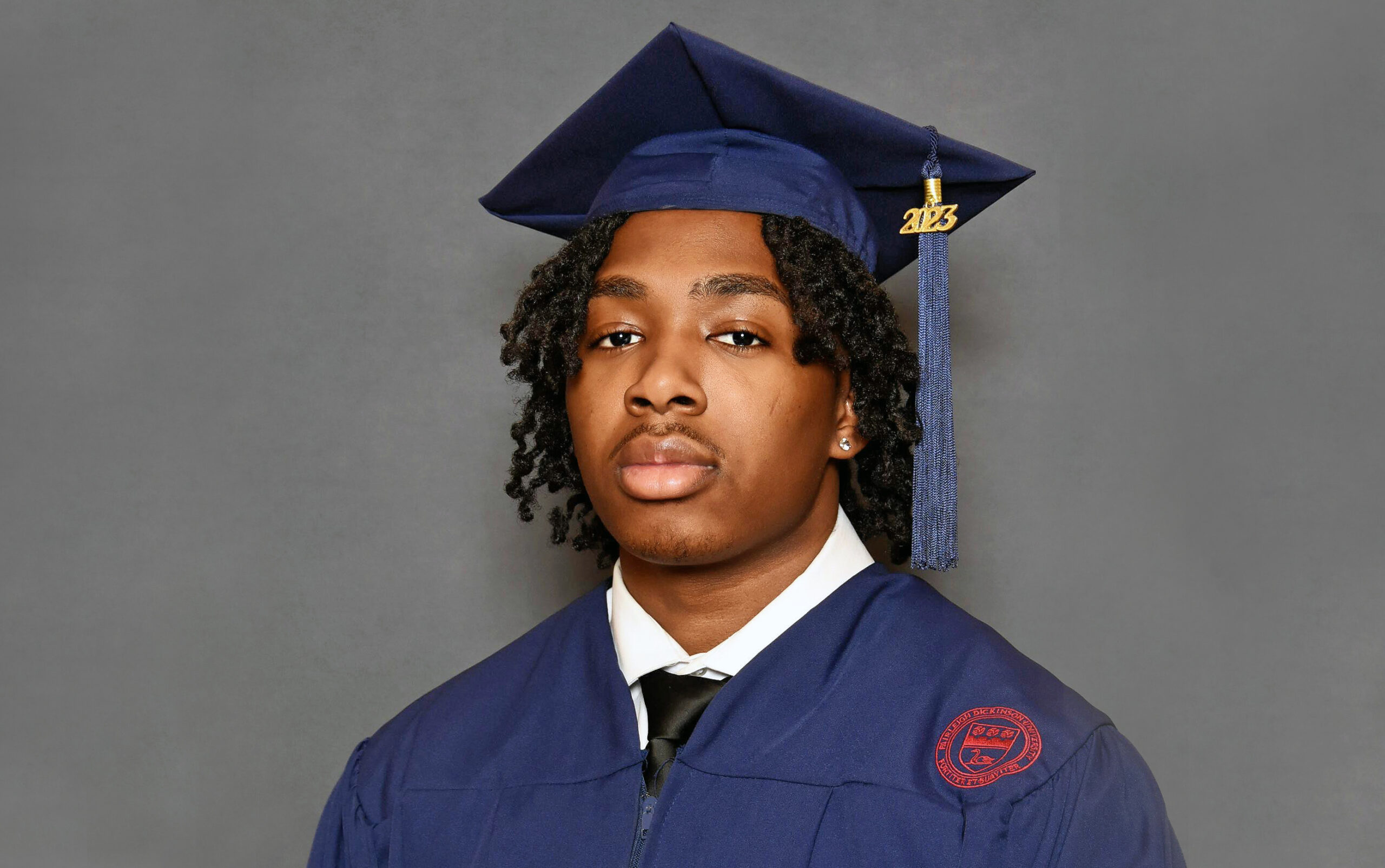 Portrait of a young man wearing a graduation cap and gown.