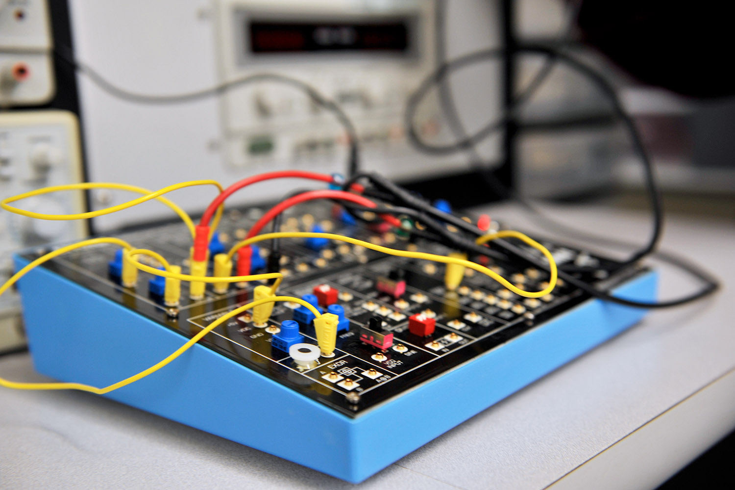 A brightly colored jumble of electrical wires sit plugged into a box in a lab.