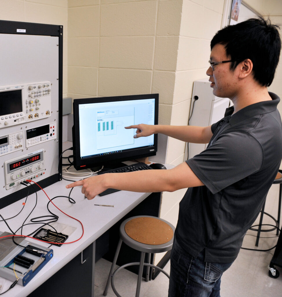 Engineering student programs machines and a computer.