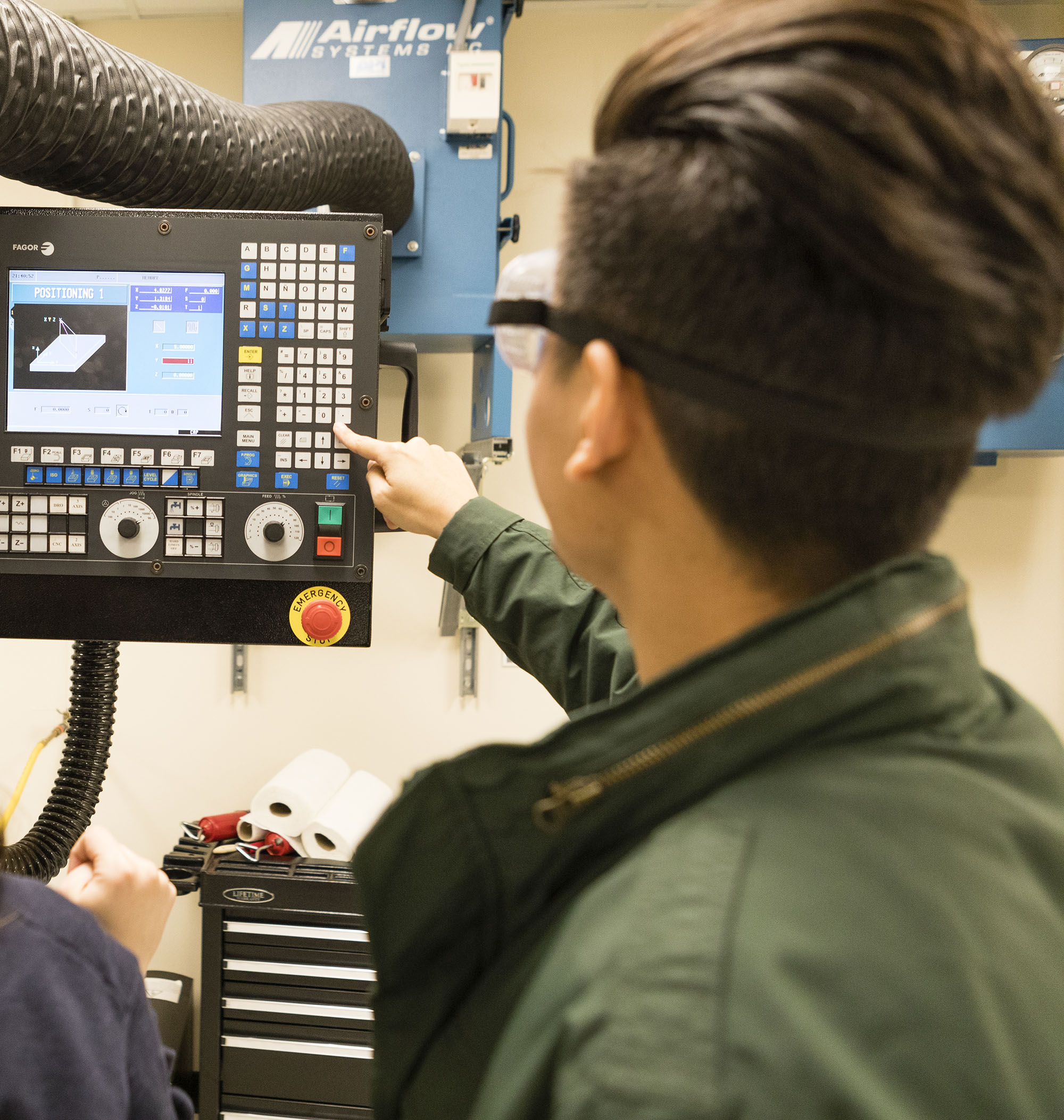 A student engineer programs a machine.