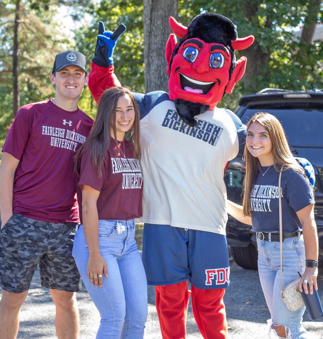 FDU alumni pose for a photo with Ian the Devil mascot.
