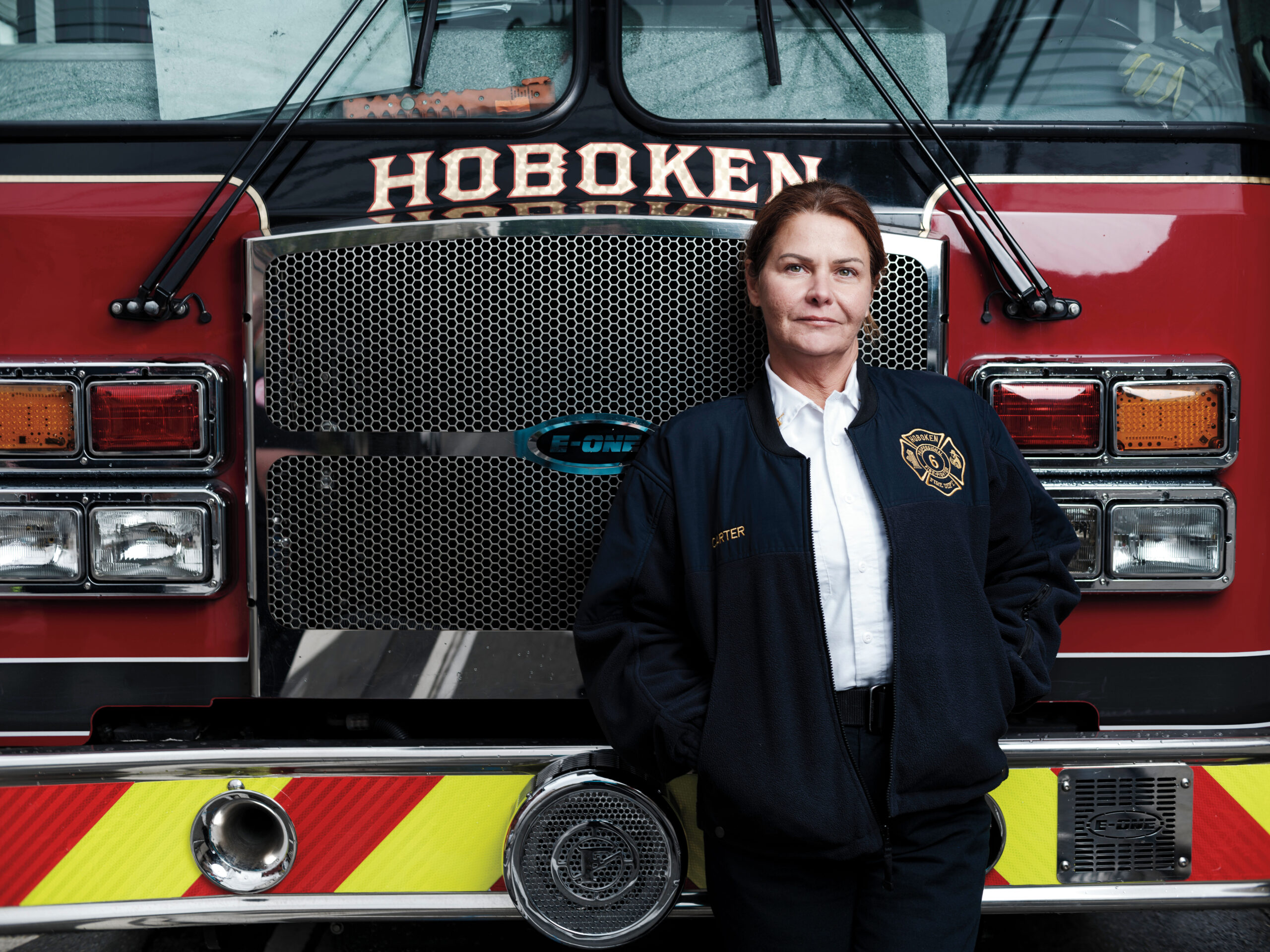 A female firefighter leans against a fire truck that's part of the Hoboken, N.J., department.