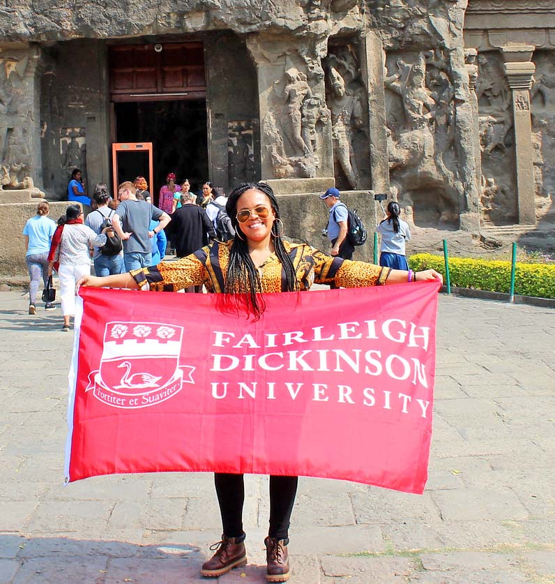 A young woman holds up an FDU flag on a trip to India in 2019.