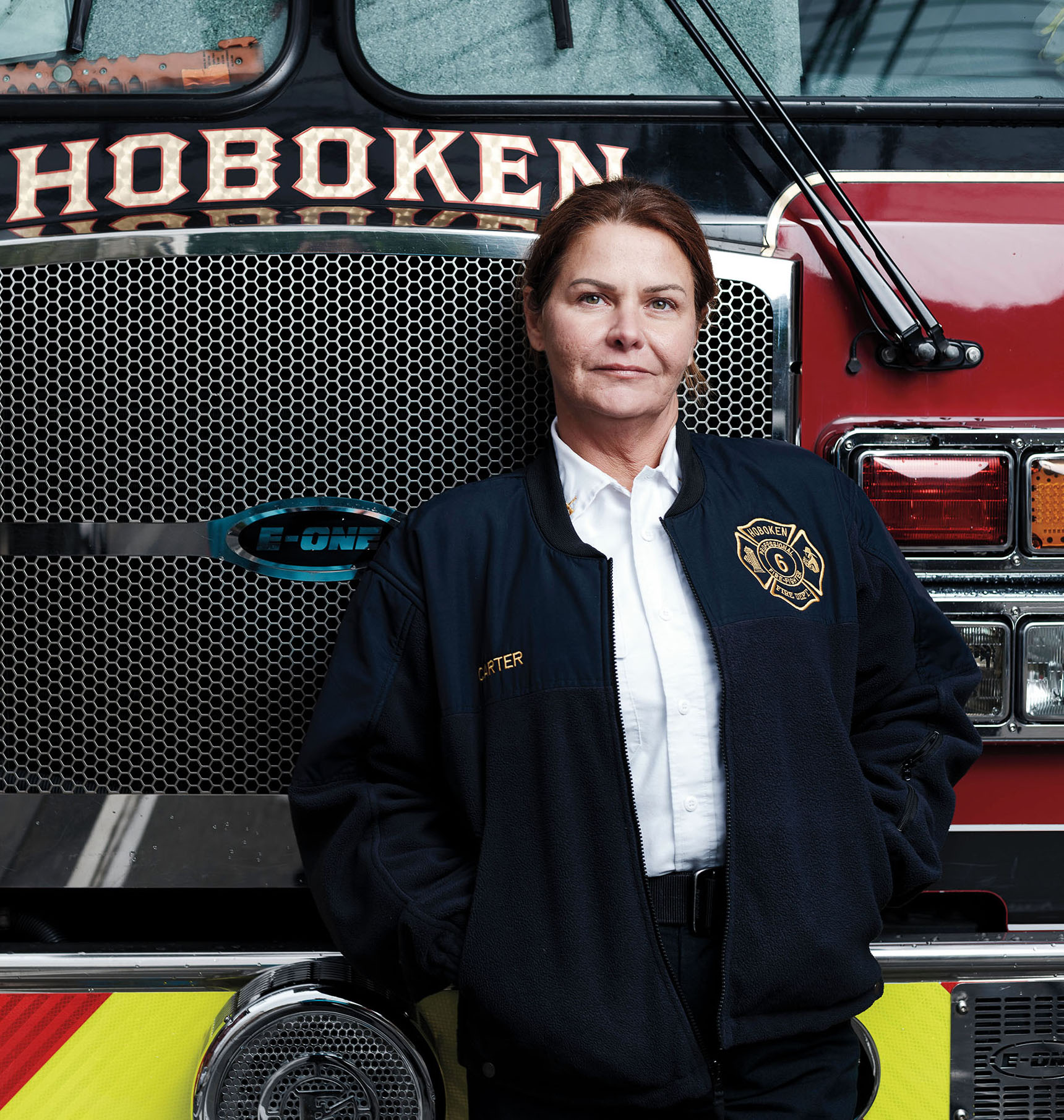 A female firefighter leans against a fire truck that's part of the Hoboken, N.J., department.