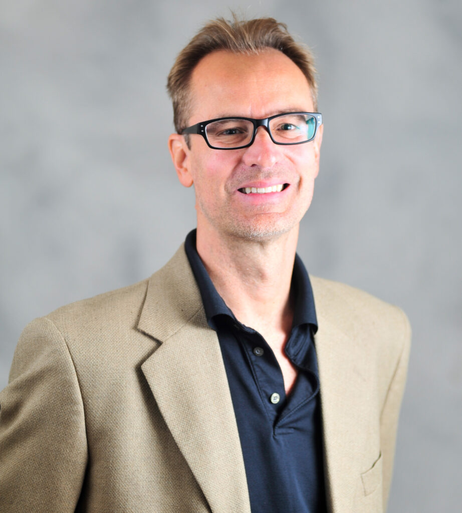 Head shot of a man wearing a sports coat and glasses.