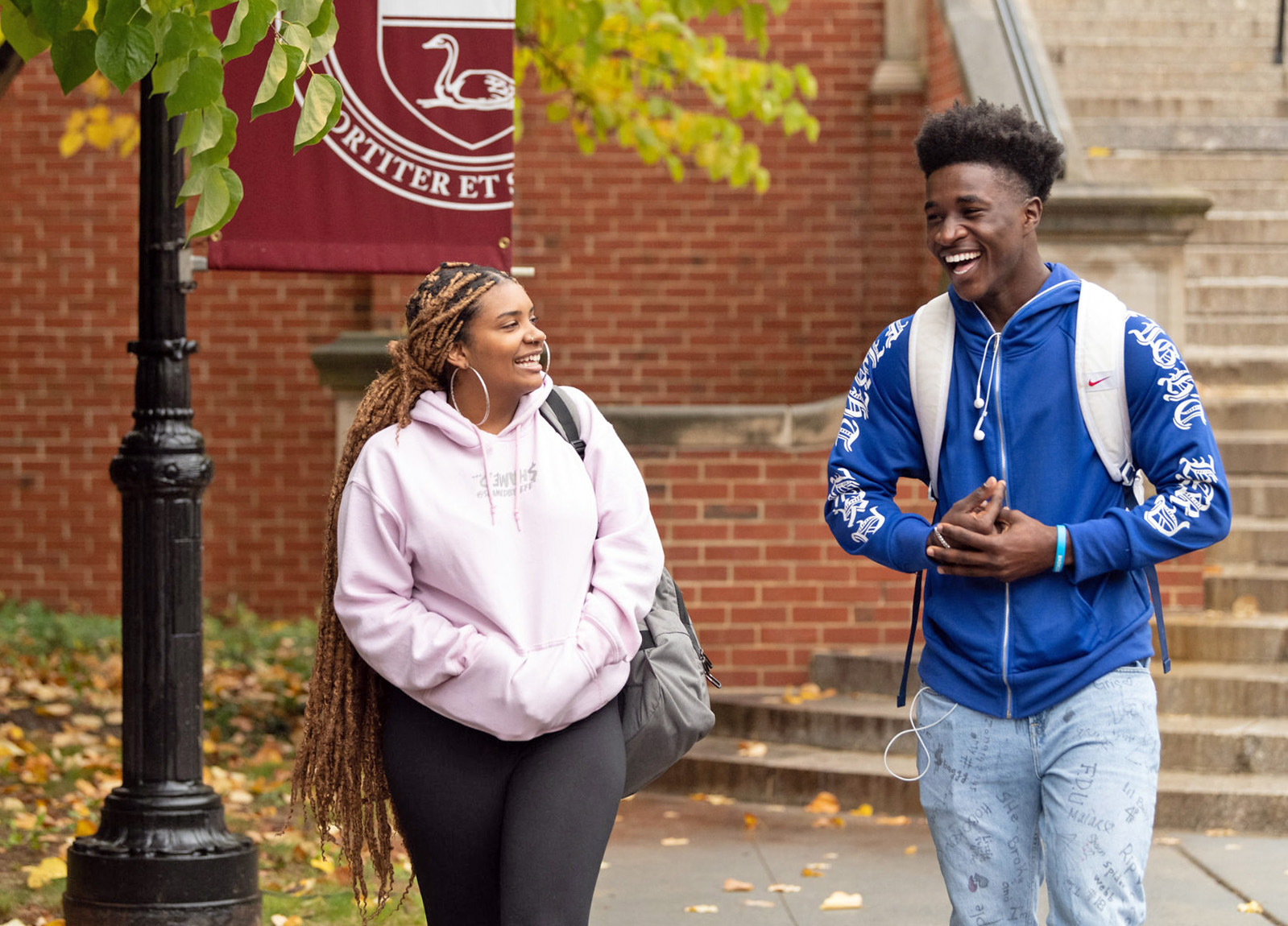 A female student and male student walk on campus, and share a laugh.