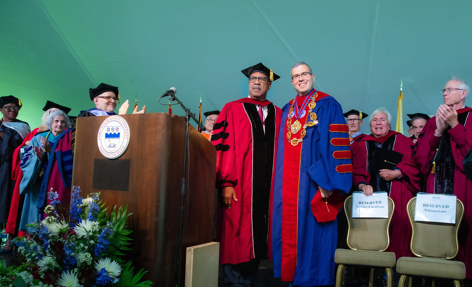 Two men in academic regalia pose on stage for a photo during the inauguration ceremony.