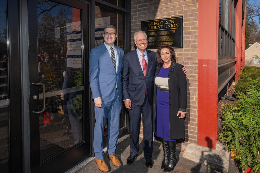 President Avaltroni with Greg Olsen and his daughter Krista stand near the new signage on the Student Union on the Metropolitan Campus.