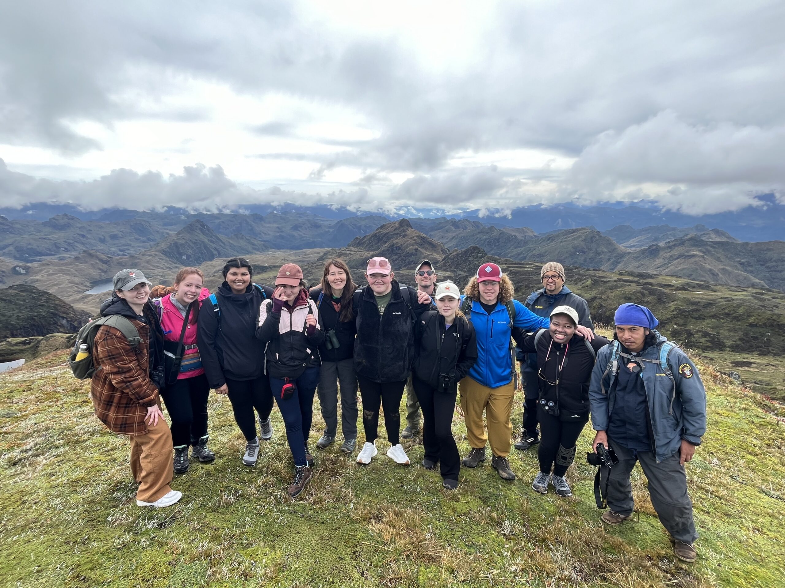 a group of students pose for the camera. there is a mountain range behind them.