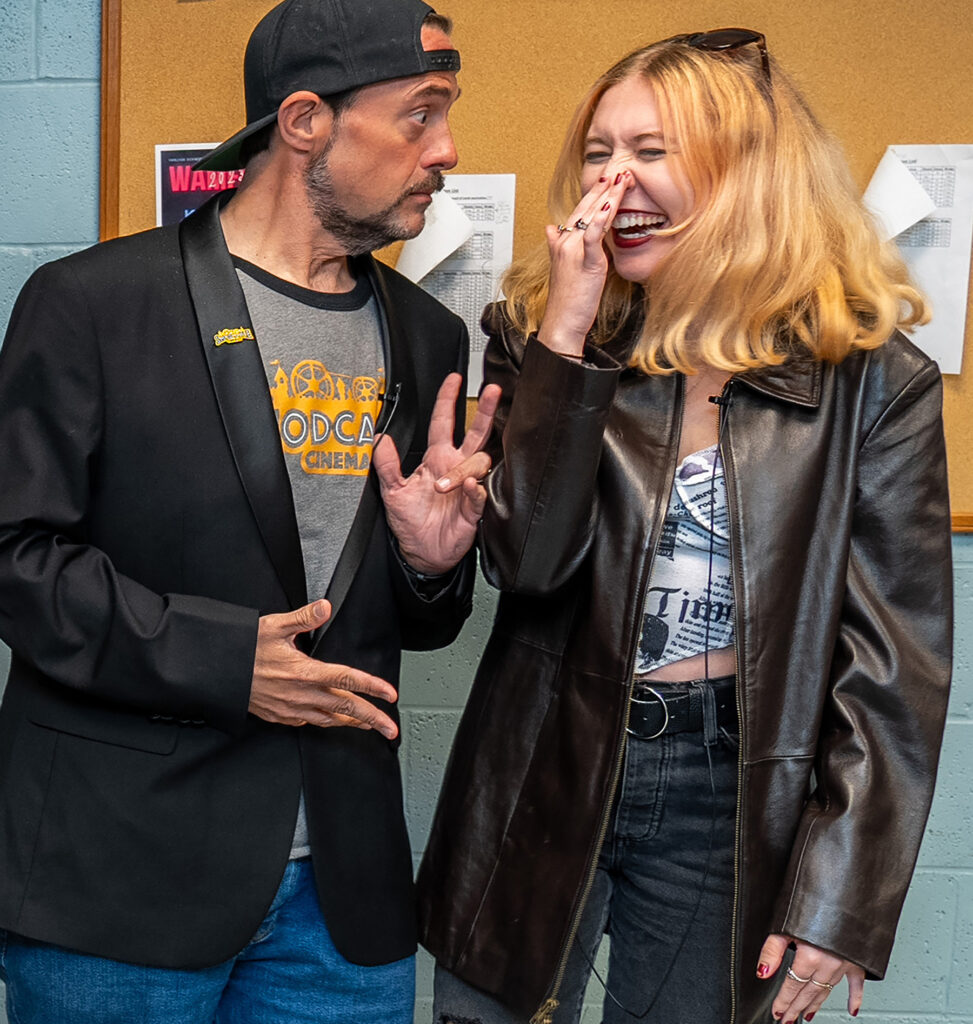 A man and a woman pose for a photo between giggles.