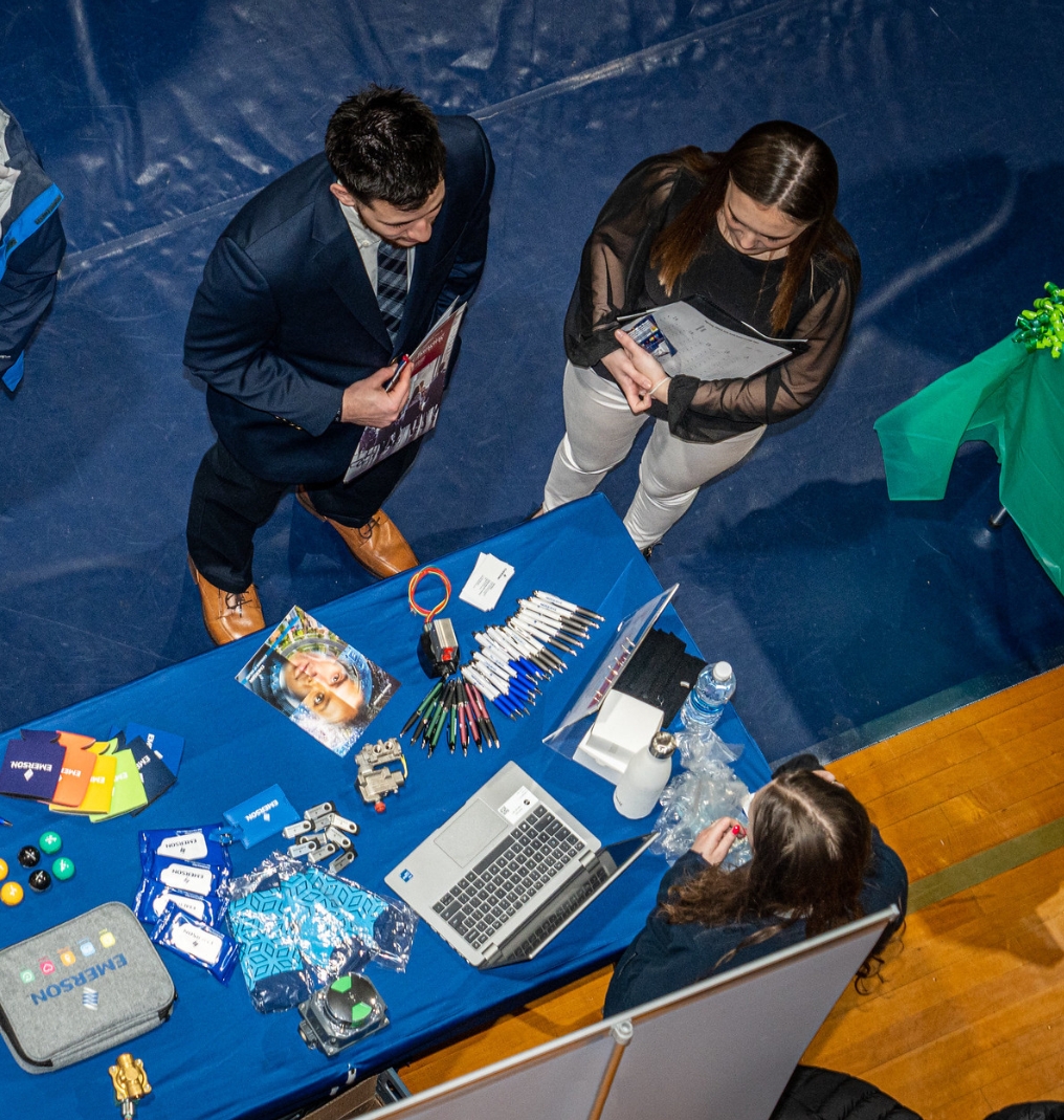 a bird's eye view of students speaking with a representative at a career fair.