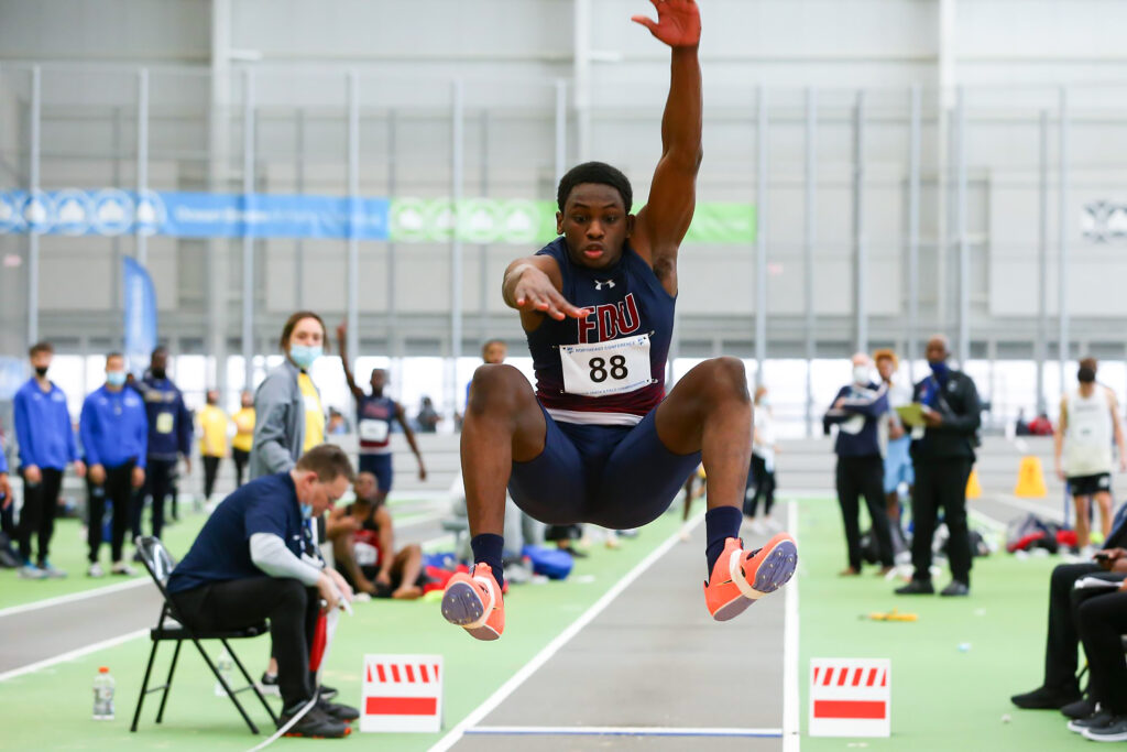 A student-athlete in an FDU Knight uniform completes a triple jump. 