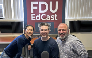 A woman and two men pose for a photo with podcast equipment in front of them.