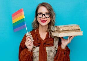a person holding books and a pride flag
