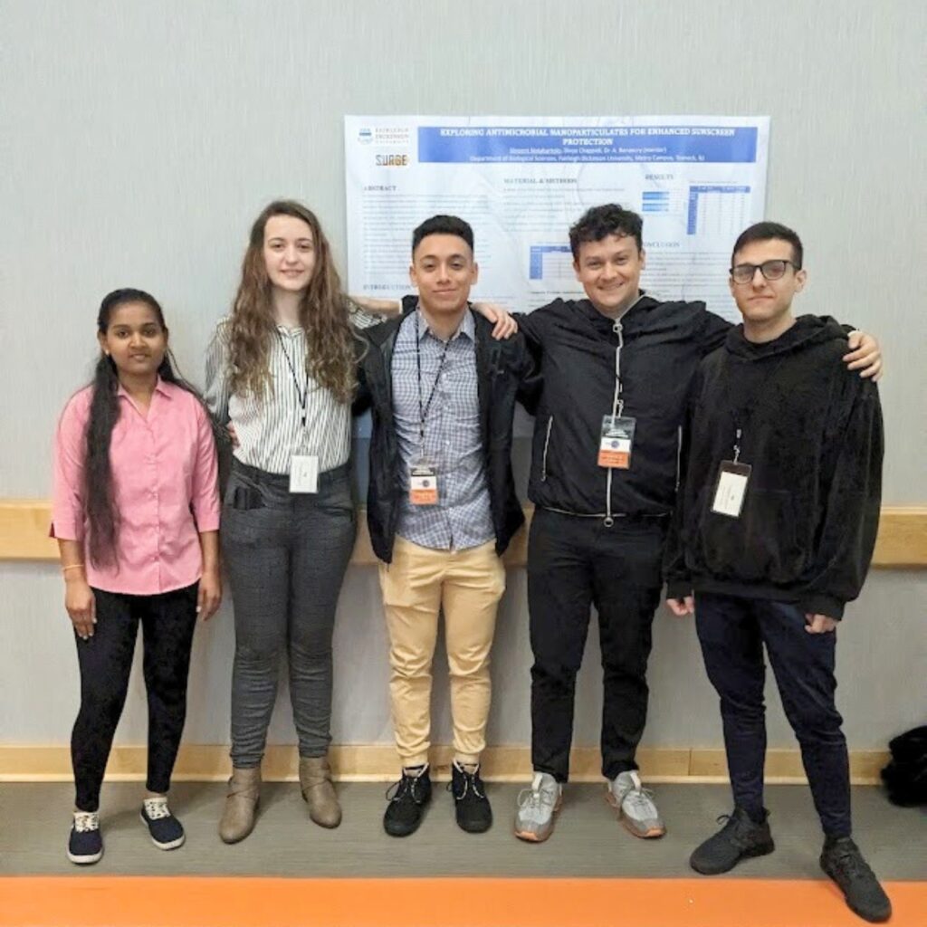 a group of students posing for the camera. they stand in front of a presentation board.