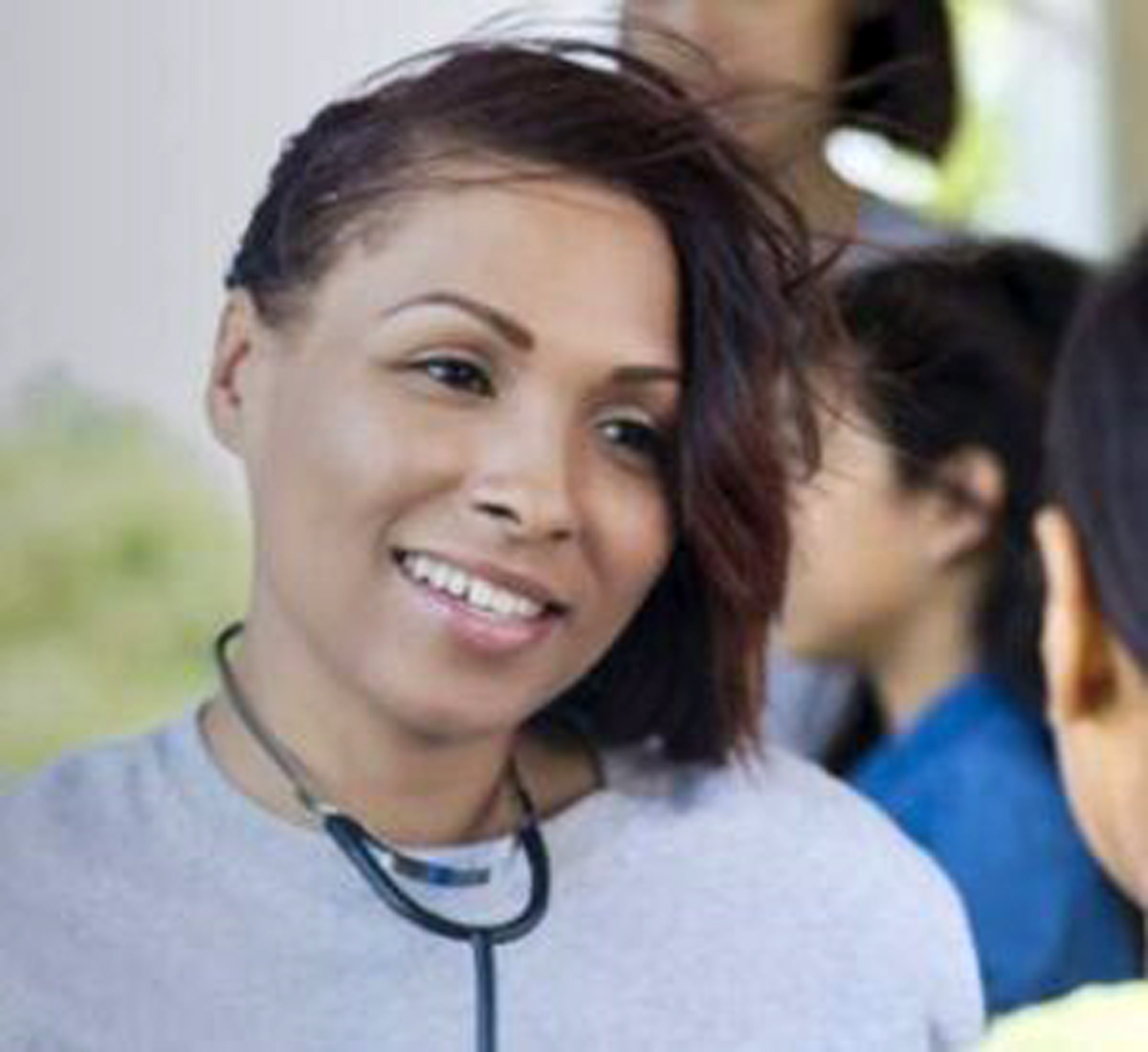 a student wears a stethoscope and smiles at someone.
