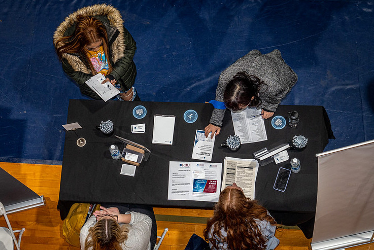 Two women stop at a table to speak to career representatives.