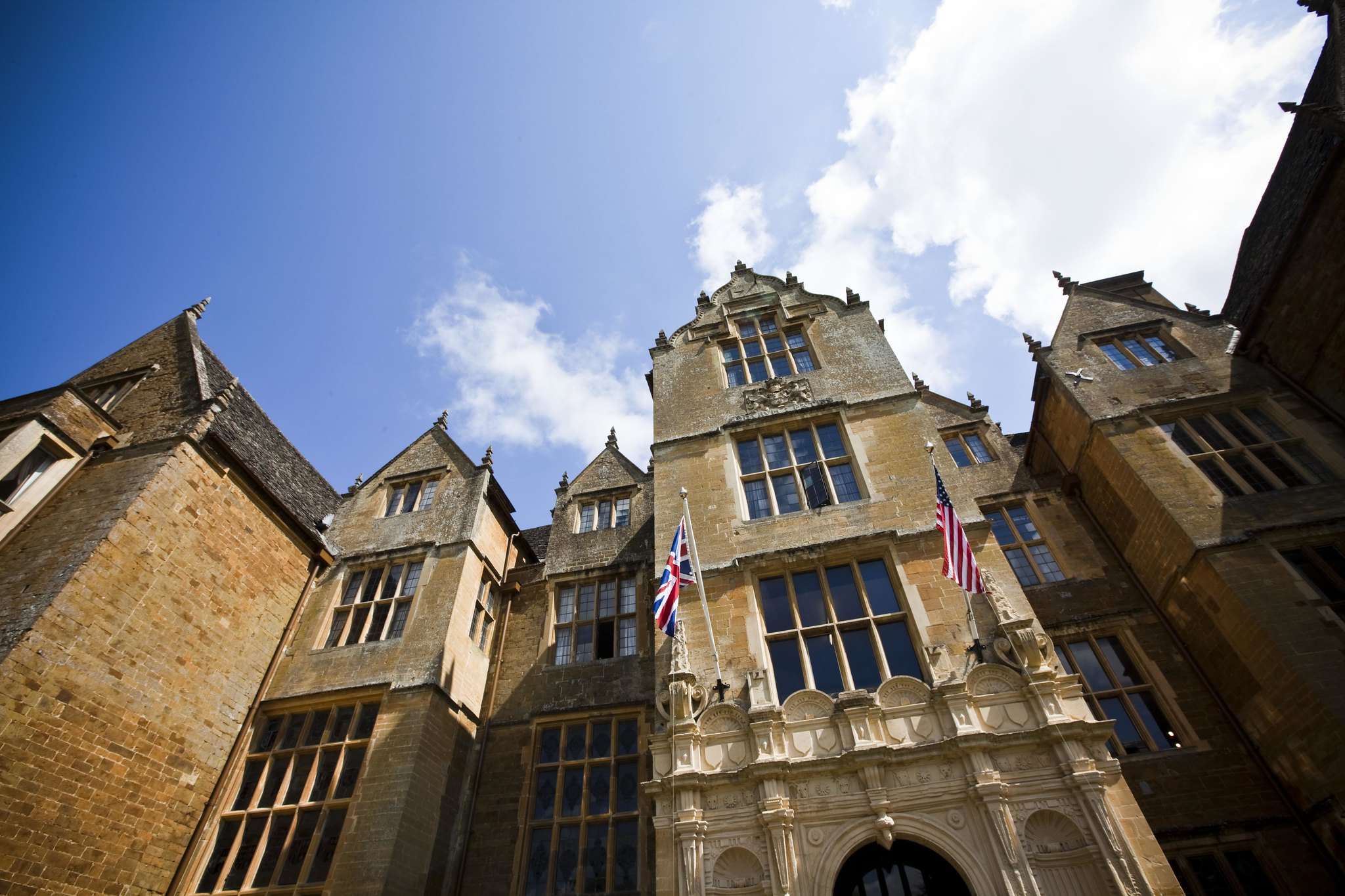 a close-up shot of the wroxton abbey. the American flag and the United Kingdom flag hang overhead.